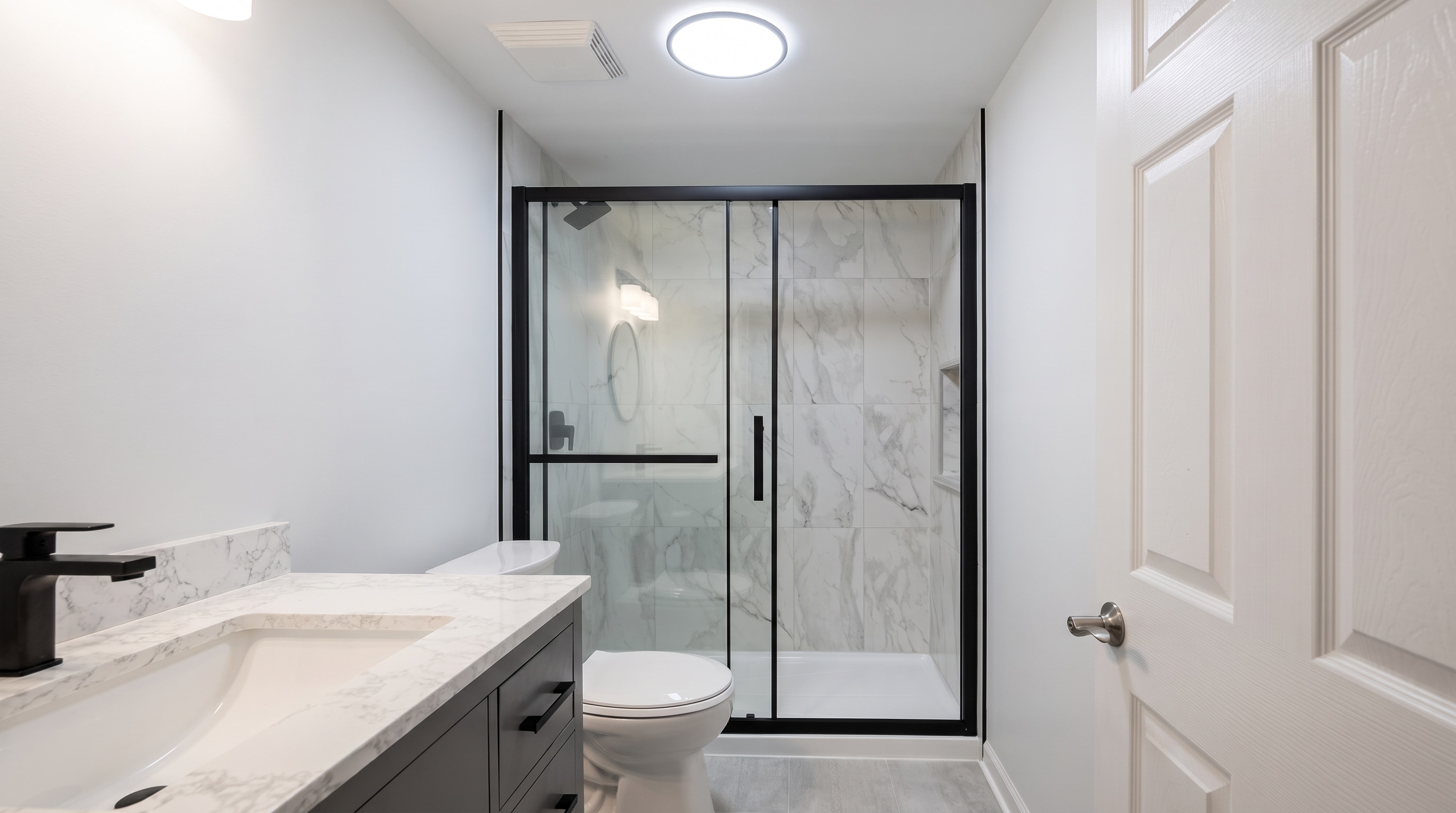 Completed bathroom with black-framed glass shower and custom vanity