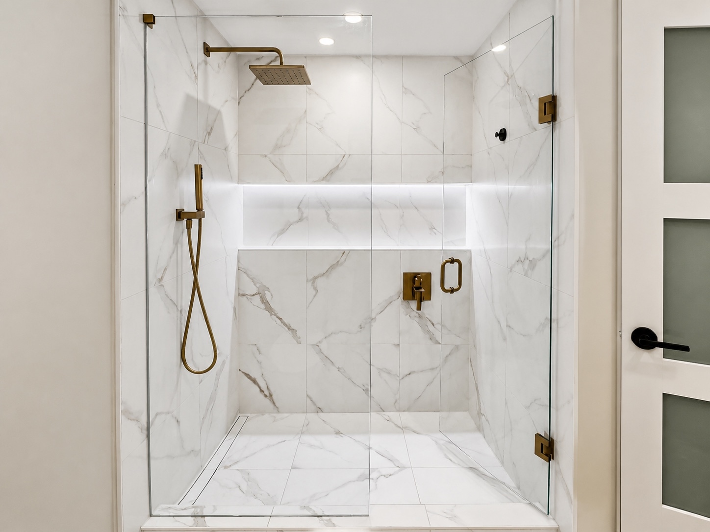 Glass shower with illuminated tiled niche